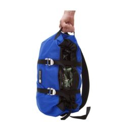 Das Bild zeigt einen blauen Metolius Seilsack. Eine Hand hält ihn von oben während er senkrecht nach unten hängt. Man sieht die äußere Hülle und die beiden Spannriemen mit den Alu Schnallen.