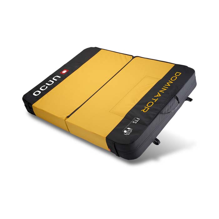 Das Bild zeigt einen großen Bouldermatten Typ, ein sogenanntes Fat Pad. Es steht schräg in Bildmitte und hat ein gelbes Center sowie schwarze Außenränder.