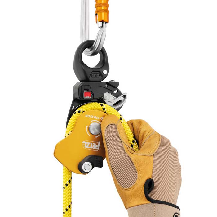Golden schwarze Petzl Pro Traxion Seilrolle mit eingelegtem gelben Seil und HAndmit Arbeitshandschuh.