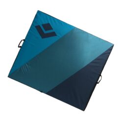 Das Bild zeigt die Black Diamond Drop Zone Bouldermatte in aufgelegtem Zustand in ihren drei Blautönen auf einem weißem Quadrat.Die Matte liegt schräg im Bild.