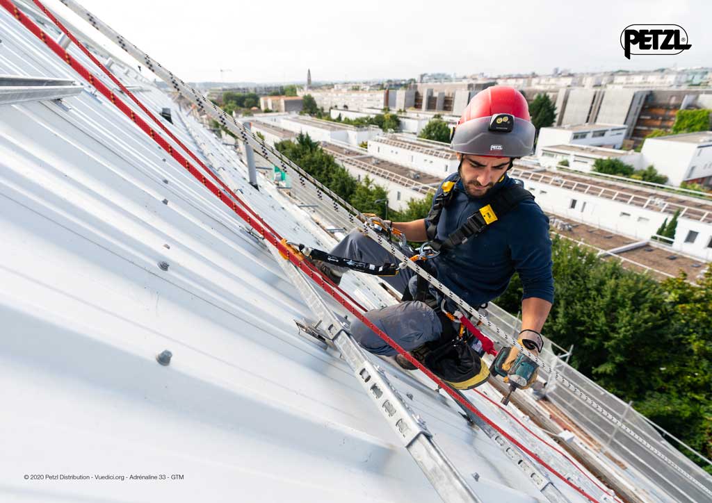mAnn beim Industrieklettern auf einem Blechdach mit Seilen, Gurt und hElm.